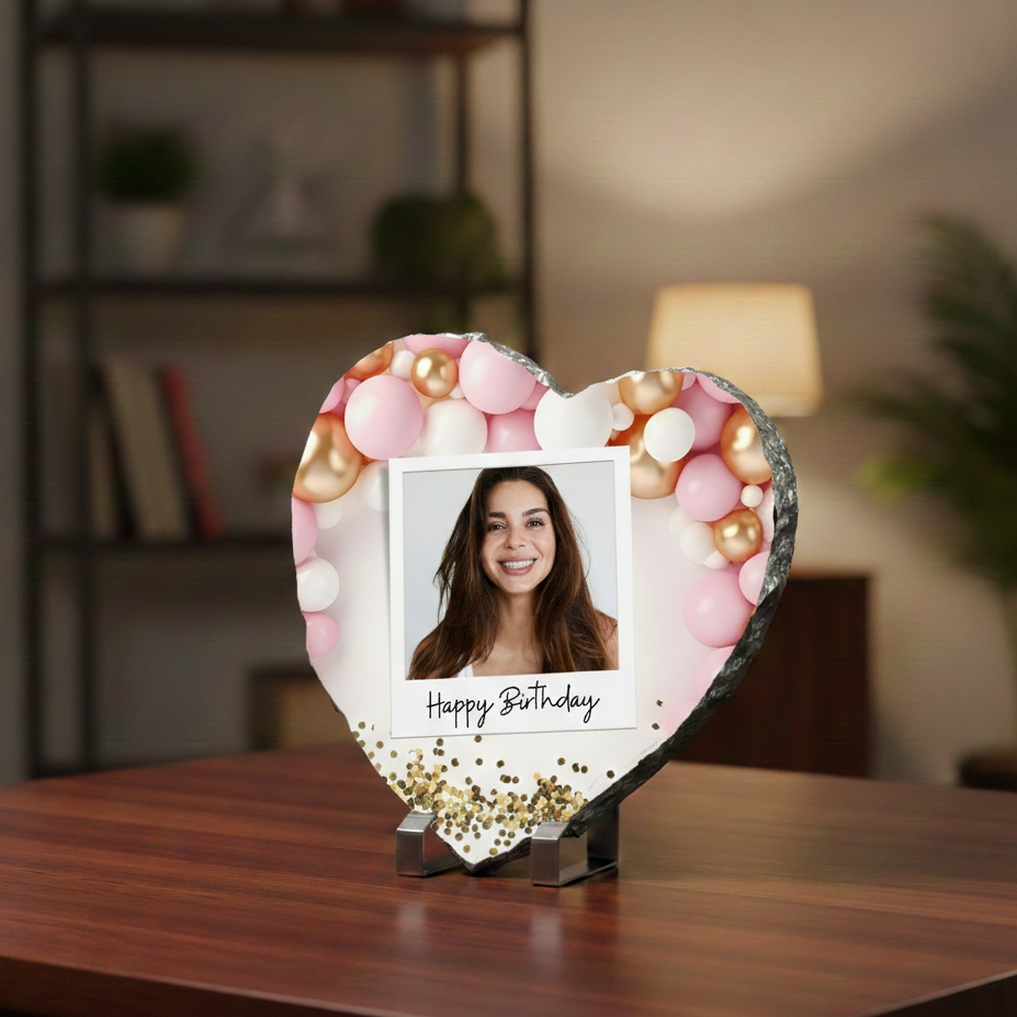 Heart-shaped decorative photo frame with a woman's photo and 'Happy Birthday' text on a wooden surface.